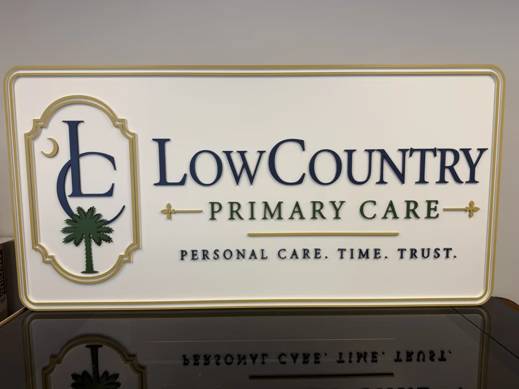 Finished Lowcountry Primary Care dimensional sign with raised navy lettering, palm tree mark and gold border
